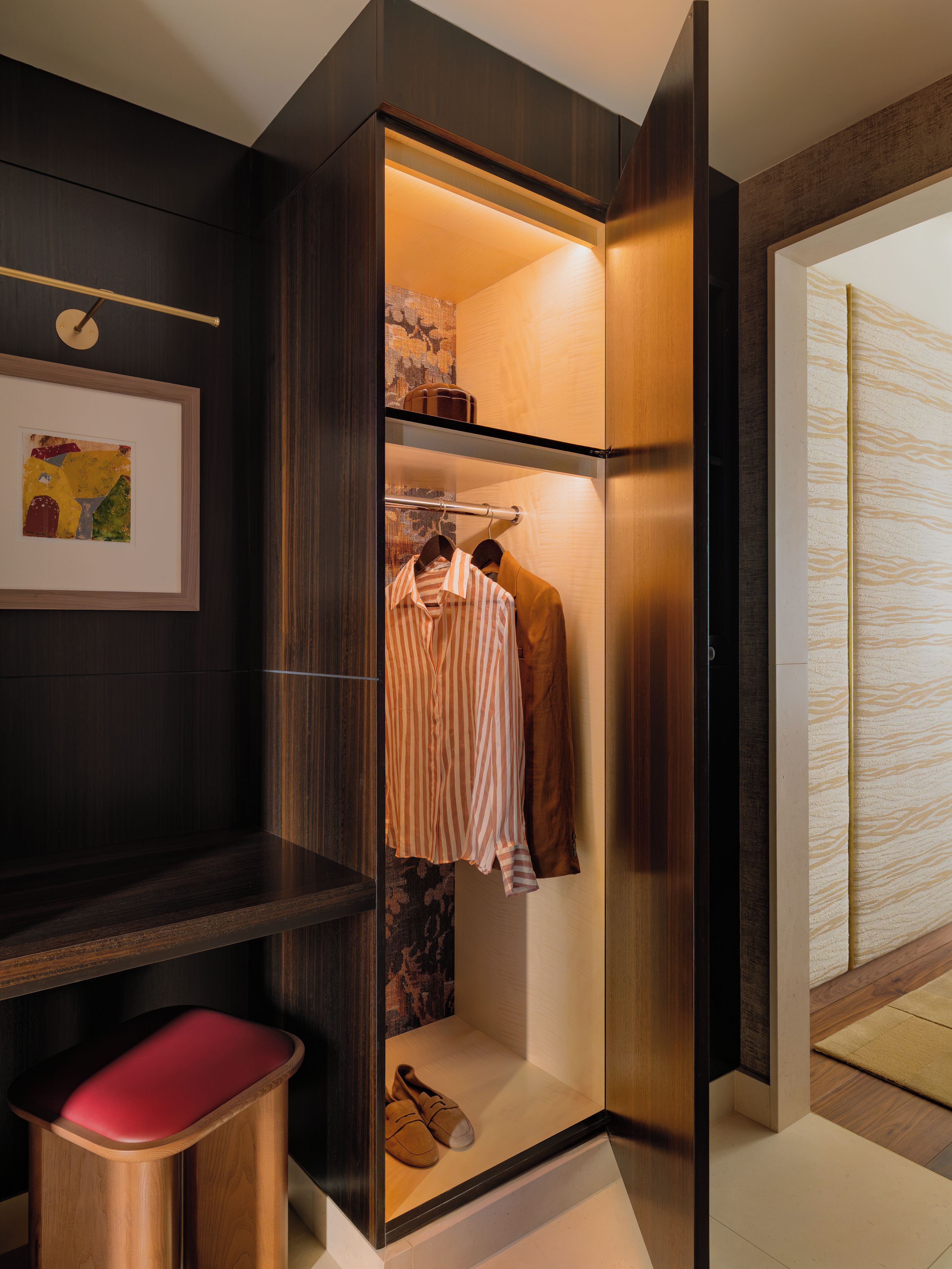 Un dressing avec espace pour suspendre les vêtements, un banc et un porte-chaussures.