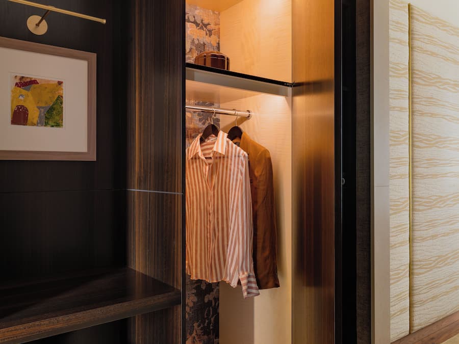 A walk-in closet with hanging space, a bench, and a shoe rack.