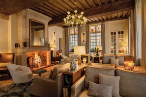 A cozy living room with a fireplace, comfortable seating, and a large chandelier. - Hotel d'Aubusson (Paris)