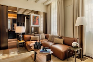 A modern living room with a brown leather sofa, a coffee table with books, a side table with a lamp, and a painting on the wall. - Hotel d'Aubusson (Paris)