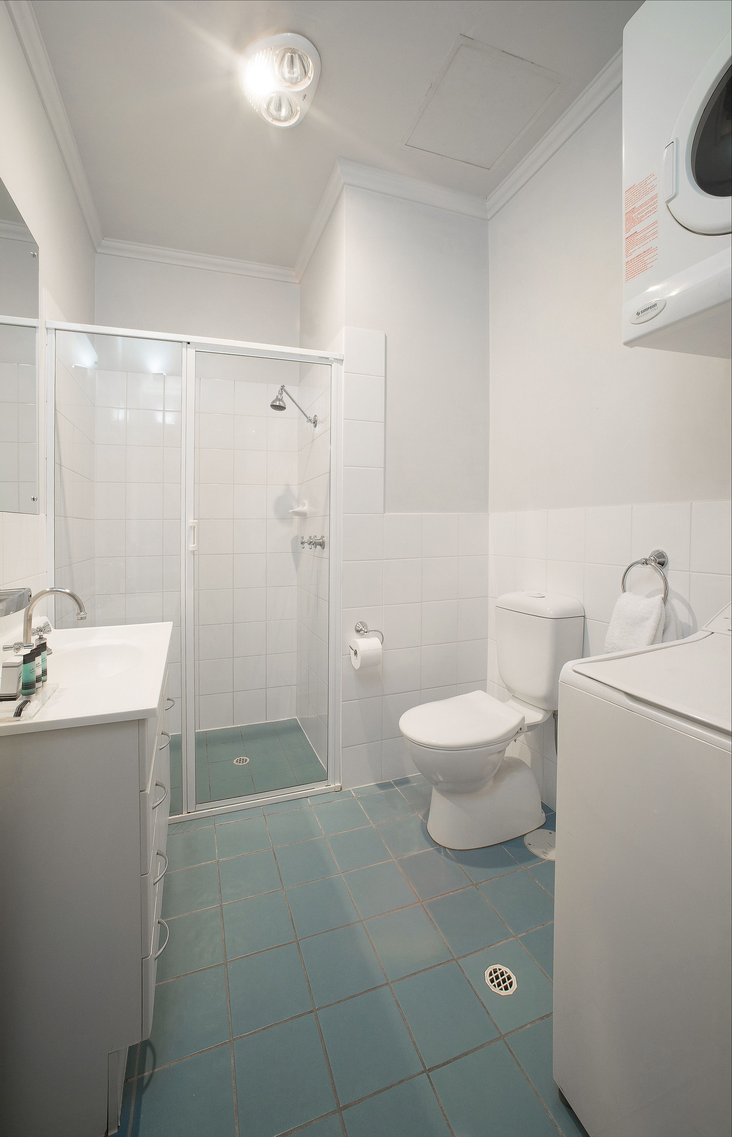 A bathroom with a shower, toilet, sink, and a white bathtub.