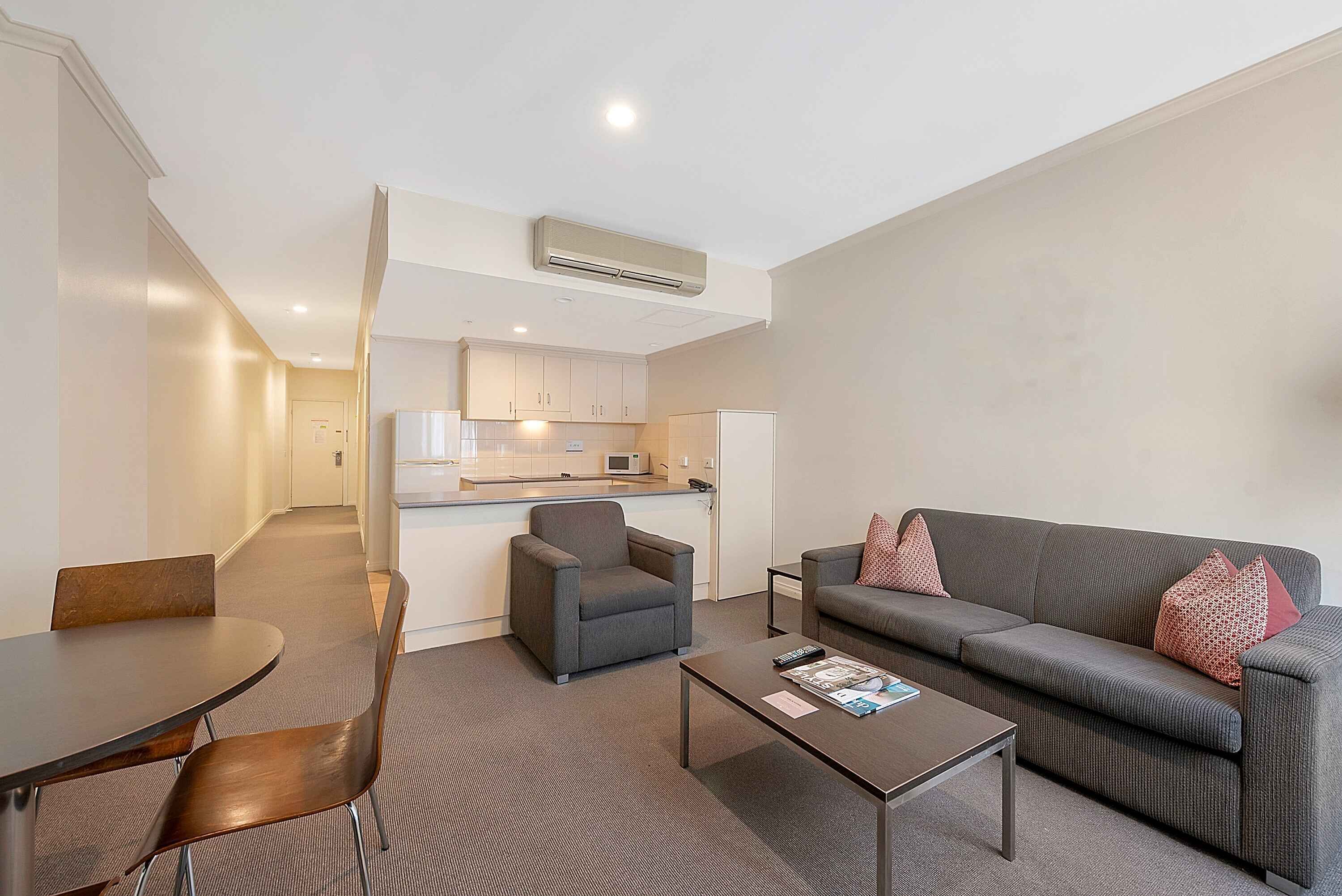 A modern living room with a grey sofa, a coffee table, and a dining area with a table and chairs.