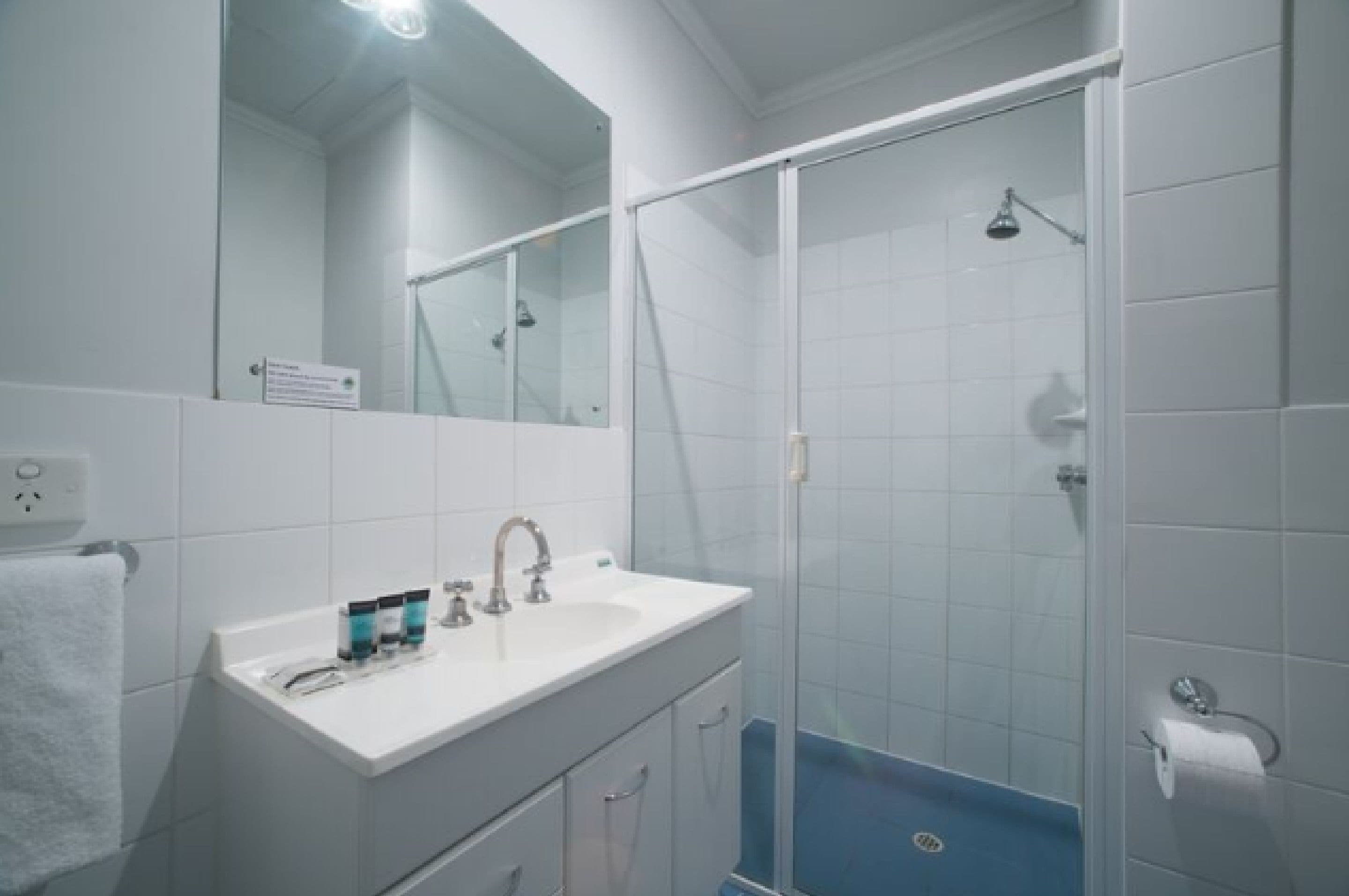 A bathroom with a white sink, mirror, and glass shower enclosure.