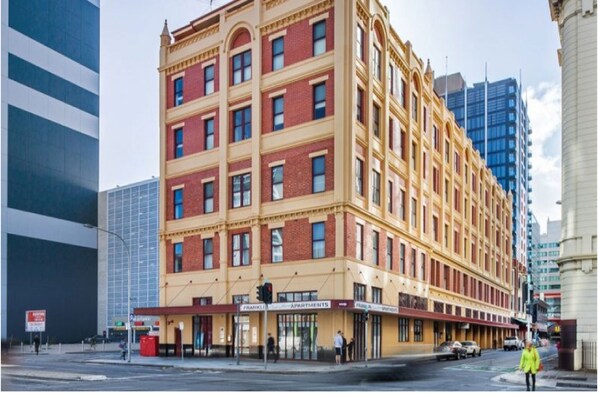 A multi-story building with a classic architectural style, featuring a ground-floor commercial space with a sign for apartments.