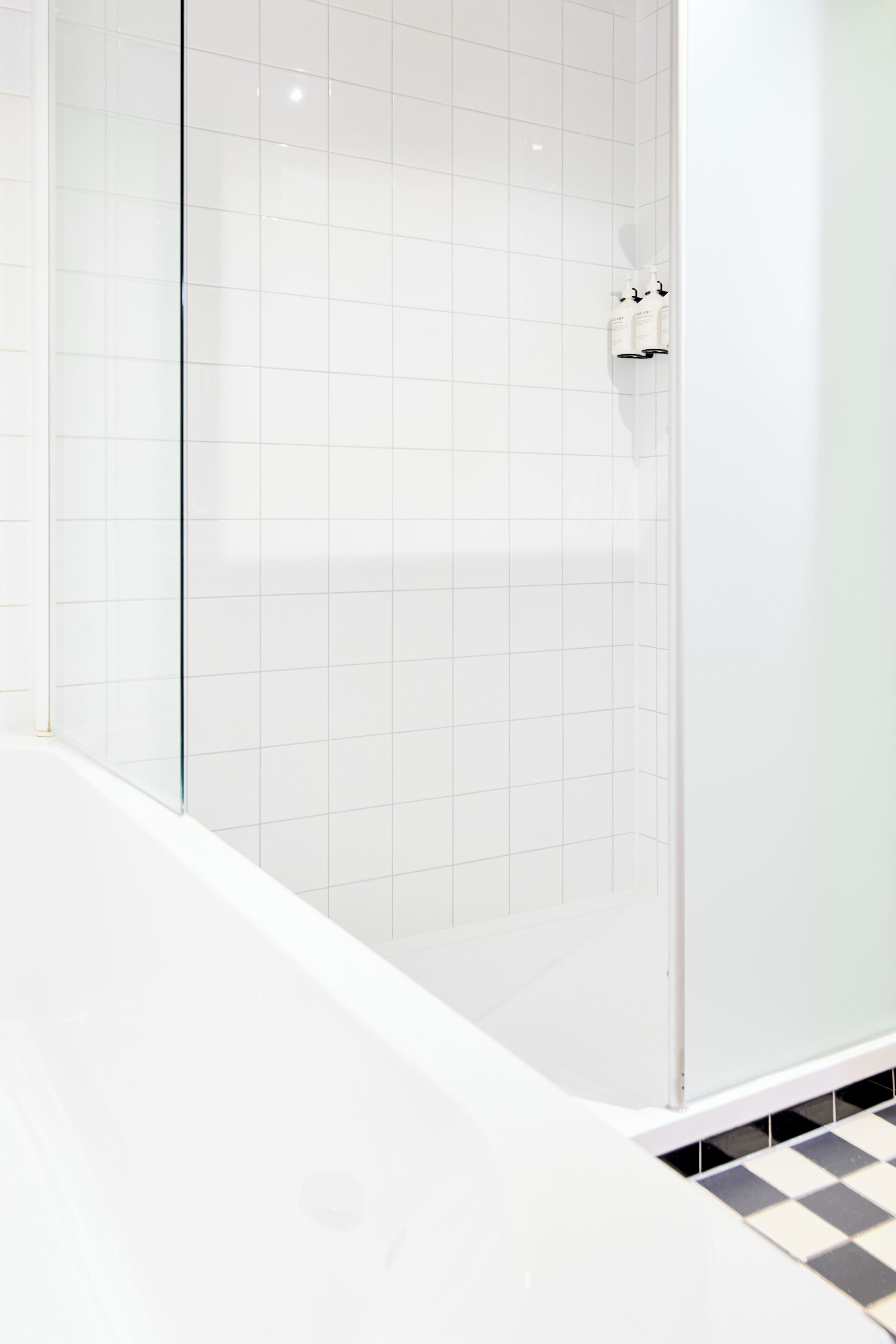 Un bagno con pareti rivestite di piastrelle bianche e una vasca da bagno bianca.