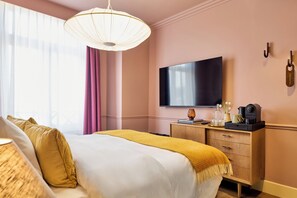 A hotel room with a bed, a television, a wooden dresser, and a window with curtains. - Paleis Hotel (The Hague)