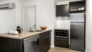 Una cocina moderna con lavavajillas, microondas, refrigerador de acero inoxidable y cafetera.