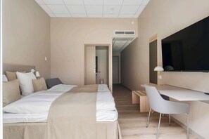 Une chambre d’hôtel moderne, dotée d’un grand lit, d’un bureau et d’une télévision.
