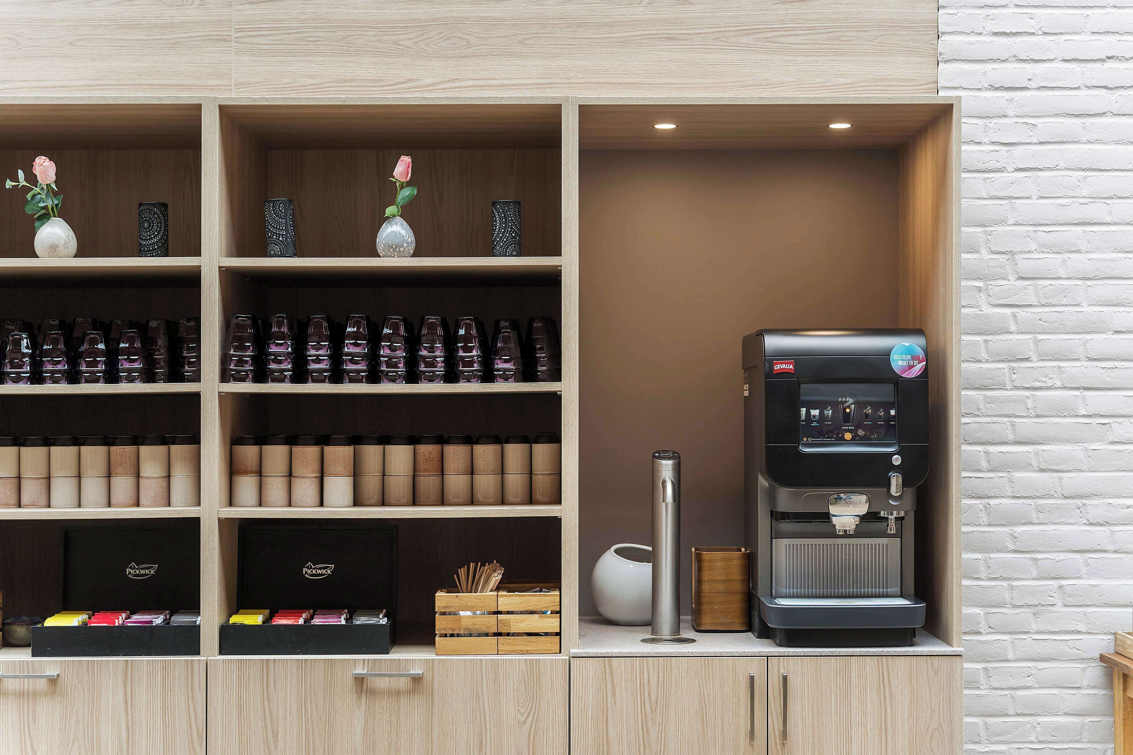 A coffee station with a coffee machine, shelves with coffee beans, and a vase with a rose.