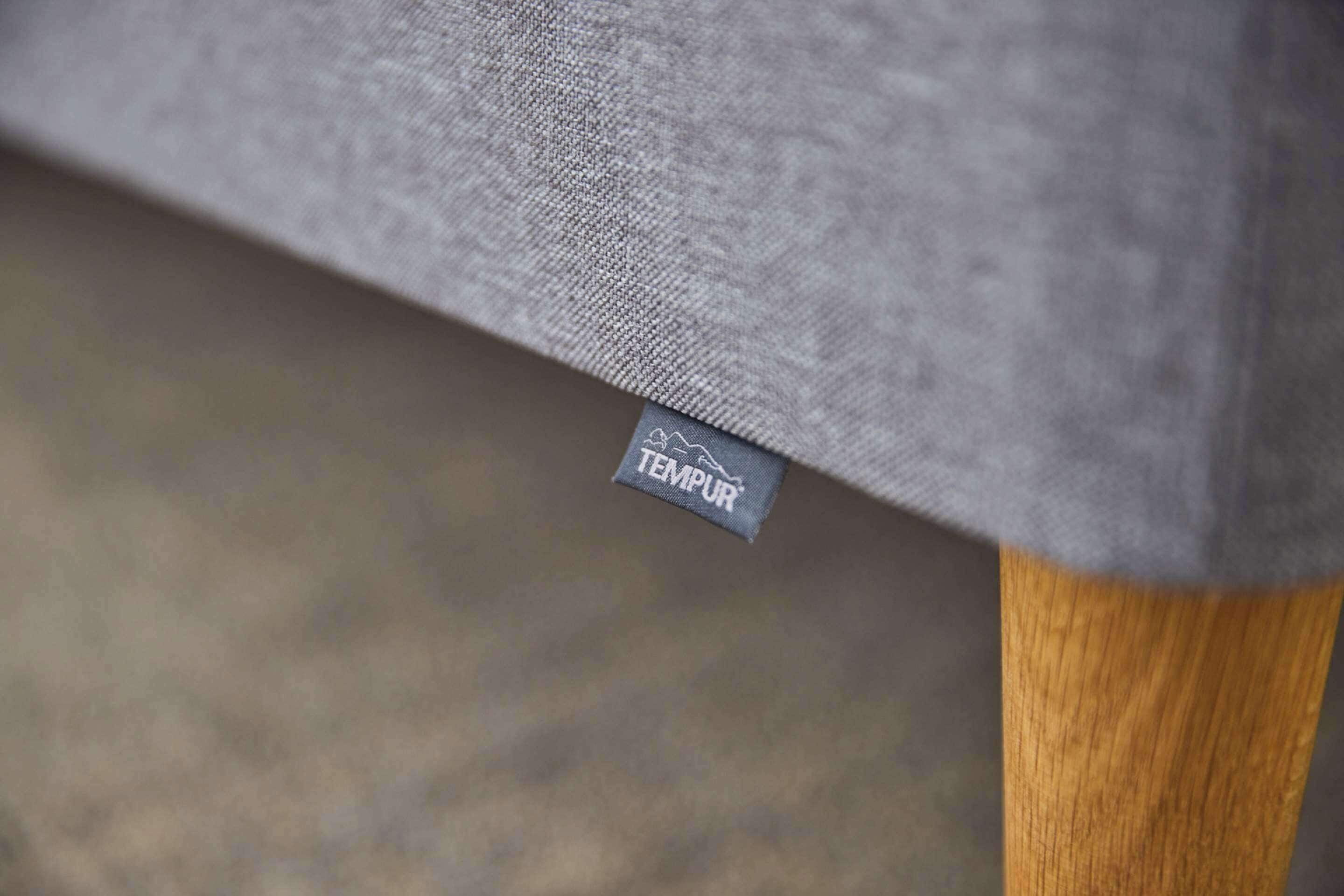A close-up of a grey fabric with a TEMPUR label, indicating a TEMPUR brand mattress.