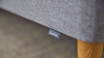 Primer plano de un tejido gris con una etiqueta TEMPUR, que indica un colchón de la marca TEMPUR.