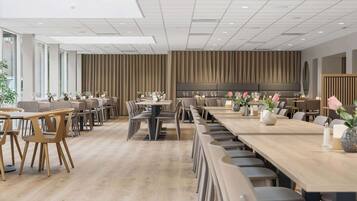 A modern dining area with long tables and chairs, a wooden floor, and a large wall with a vertical panel design.