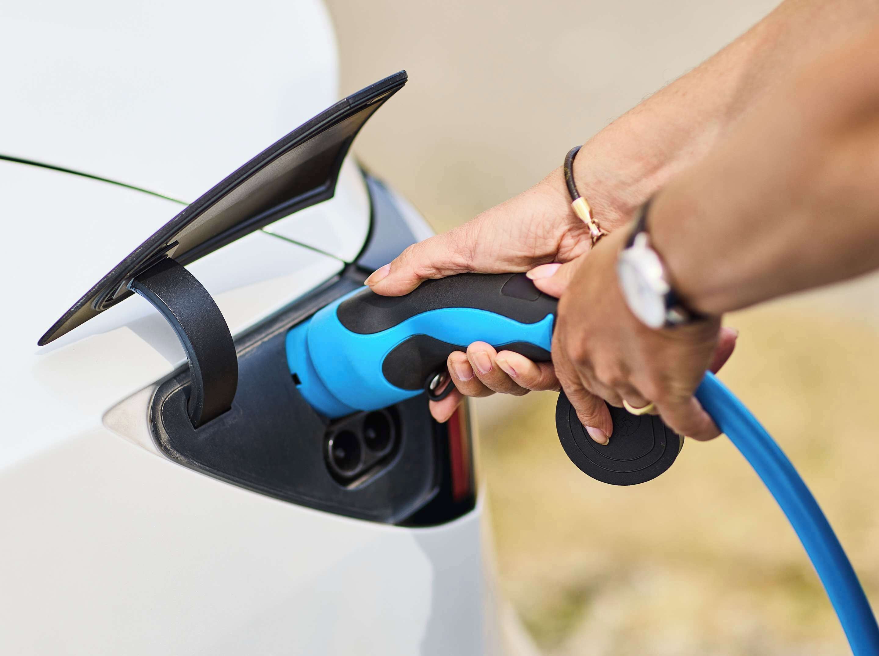 A person plugging a charging cable into a car's charging port.