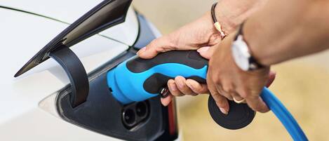 A person plugging a charging cable into a car's charging port.