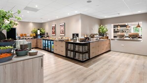 A modern kitchen with a central island, wooden cabinets, and a variety of food items and utensils. - Best Western Plus Hotel Odense (Odense)