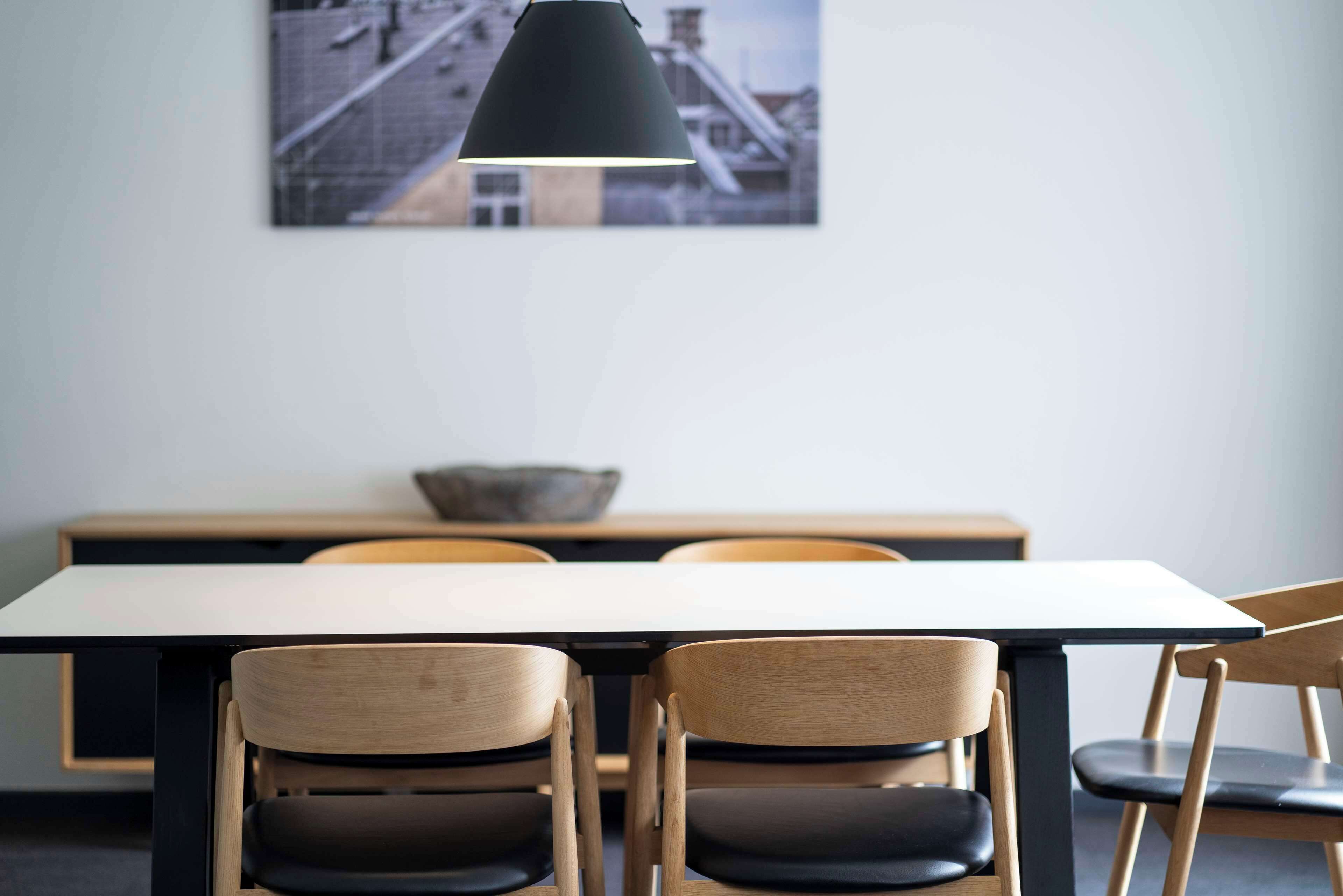 Un coin repas comprenant une table et des chaises, un luminaire suspendu et un tableau accroché au mur.