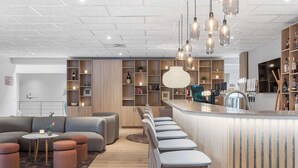 A modern kitchen with a bar area, wooden cabinets, and pendant lighting. - Best Western Plus Hotel Odense (Odense)
