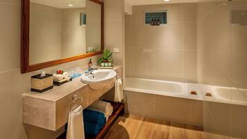 A modern bathroom with a large mirror, two sinks, a bathtub, and a small shelf with toiletries.