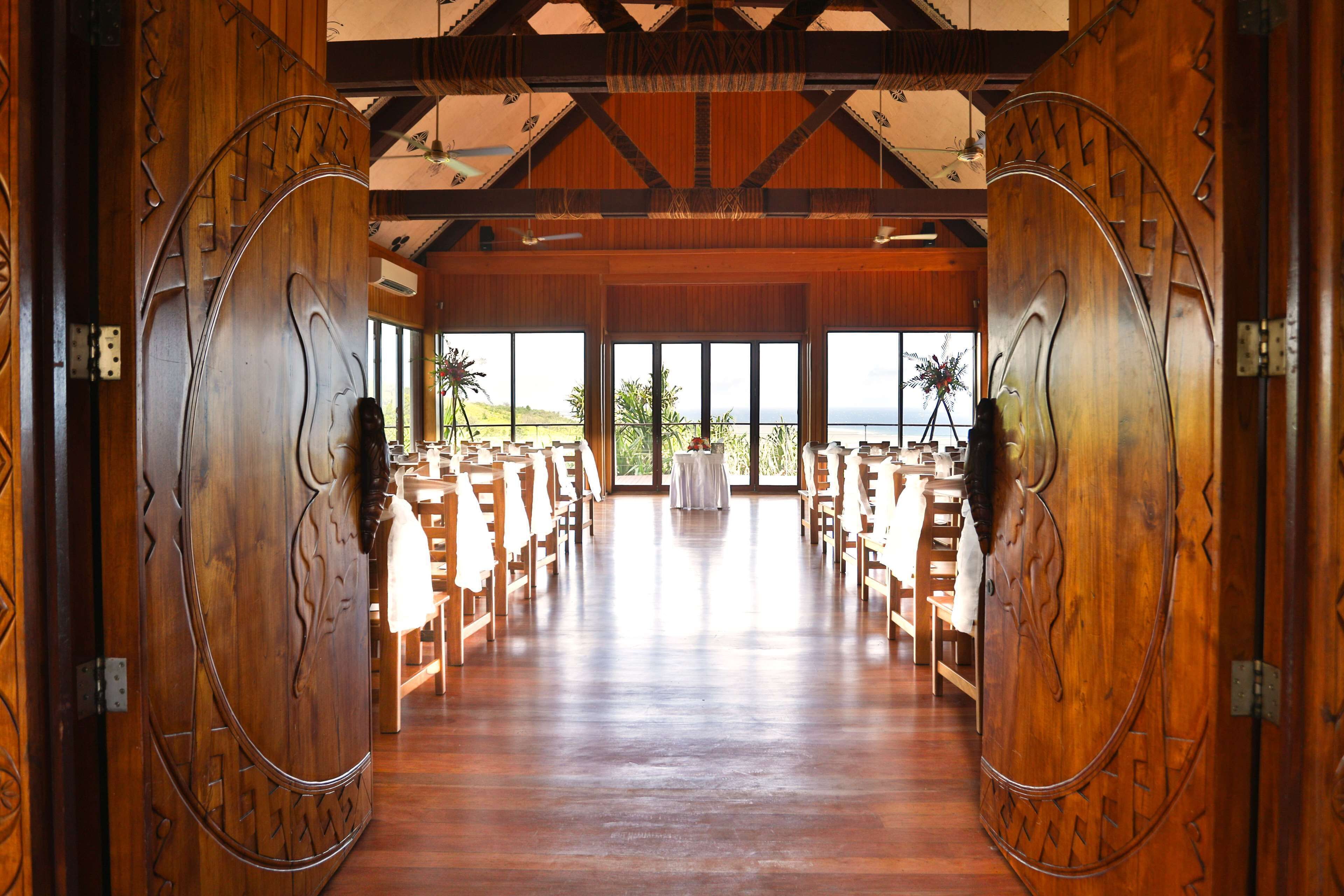 A wooden interior with a high ceiling, large windows, and a view of the outdoors.