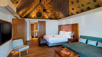 Een hotelkamer met een gestreept plafond, een bed, een bank, een televisie en een houten vloer.