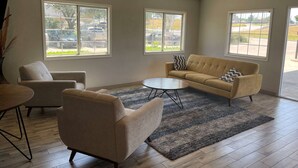 A spacious living room with a beige sofa, armchairs, and a coffee table. Large windows provide views of the outside. - Days Inn by Wyndham Mesquite Rodeo TX (Mesquite)