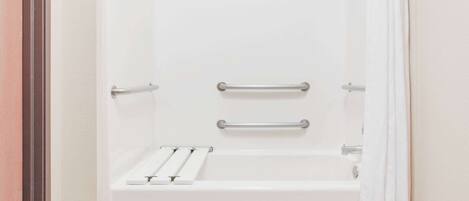 A white bathtub with two grab bars and a shelf.