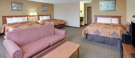 A hotel room with two beds, a sofa, a table, and artwork on the walls.