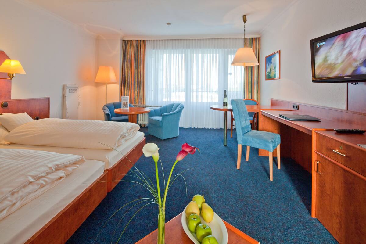 Een hotelkamer met een bed, een bureau, een stoel, een televisie en een schaal fruit.