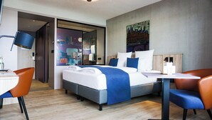 A modern hotel room with a bed, a desk, and two chairs. - Apartment-Hotel Hamburg Mitte (Hamburg)
