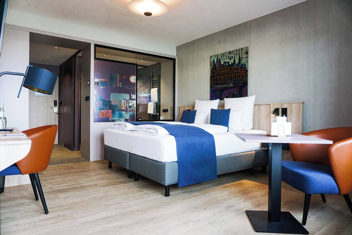 Een moderne hotelkamer met een bed, een bureau en twee stoelen.