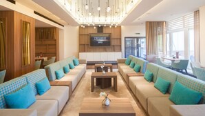 A modern lounge area with sofas, tables, and a TV screen displaying "EXCLUSIV SKY". - Apartment-Hotel Hamburg Mitte (Hamburg)