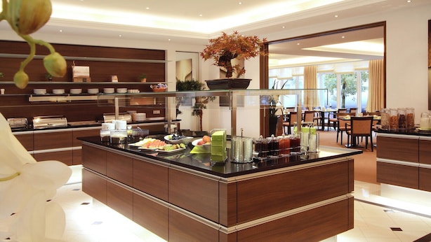 A modern kitchen with a central island, buffet setup, and a dining area with chairs and tables. - Apartment-Hotel Hamburg Mitte (Hamburg)