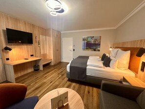 Una habitación de hotel moderna con cama, escritorio, televisión y un cuadro en la pared.