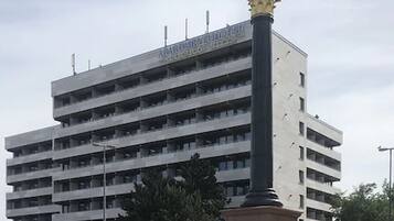 Ein mehrstöckiges Gebäude mit einer Statue auf einem Sockel davor.
