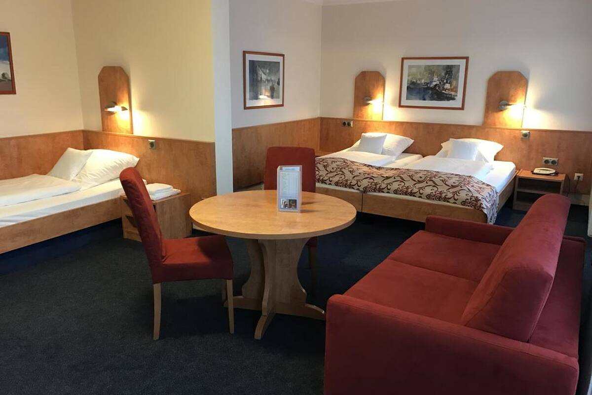 Een hotelkamer met een eenpersoonsbed, een slaapbank, een tafel en twee wandlampen.