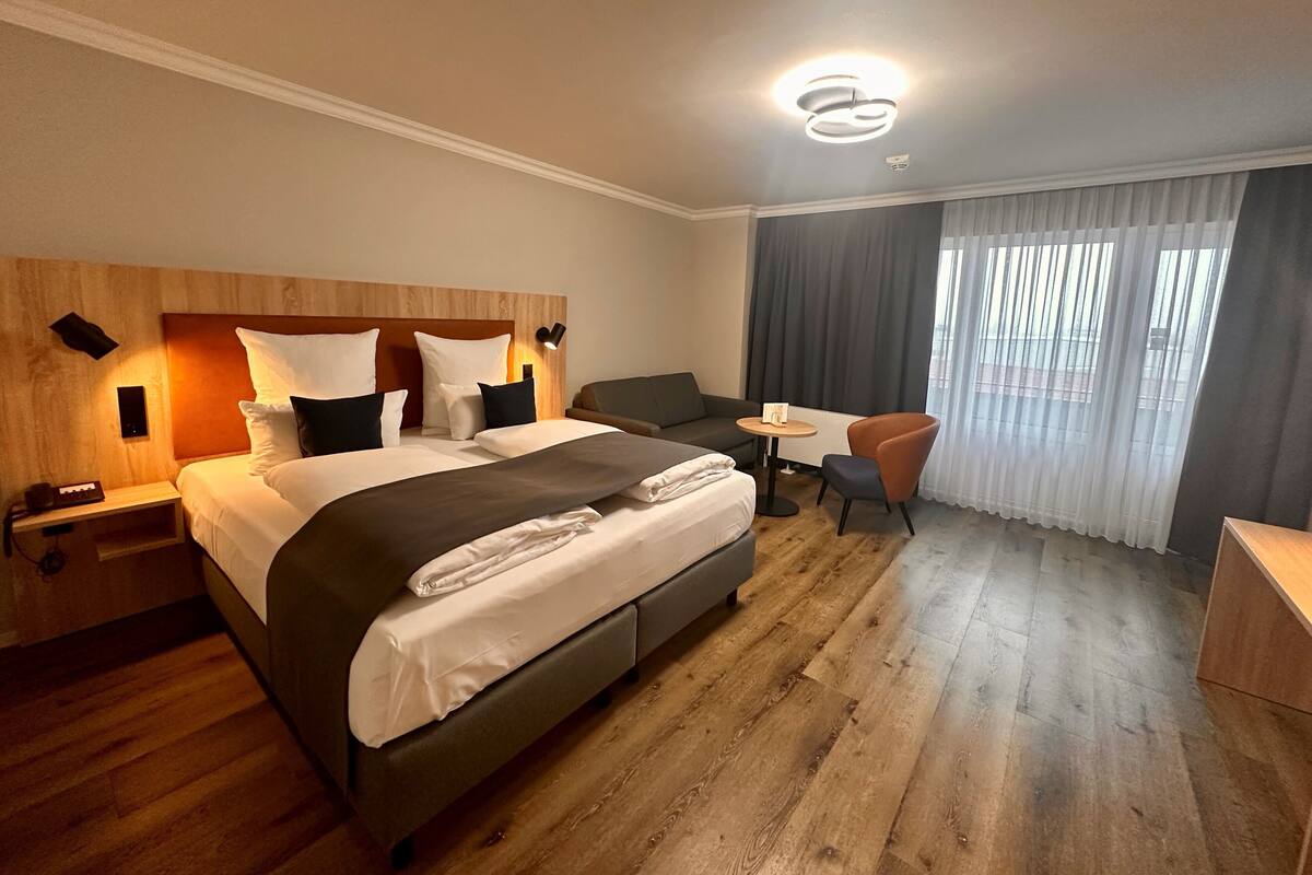 Een hotelkamer met een groot bed, een bank, een kleine tafel en een stoel.