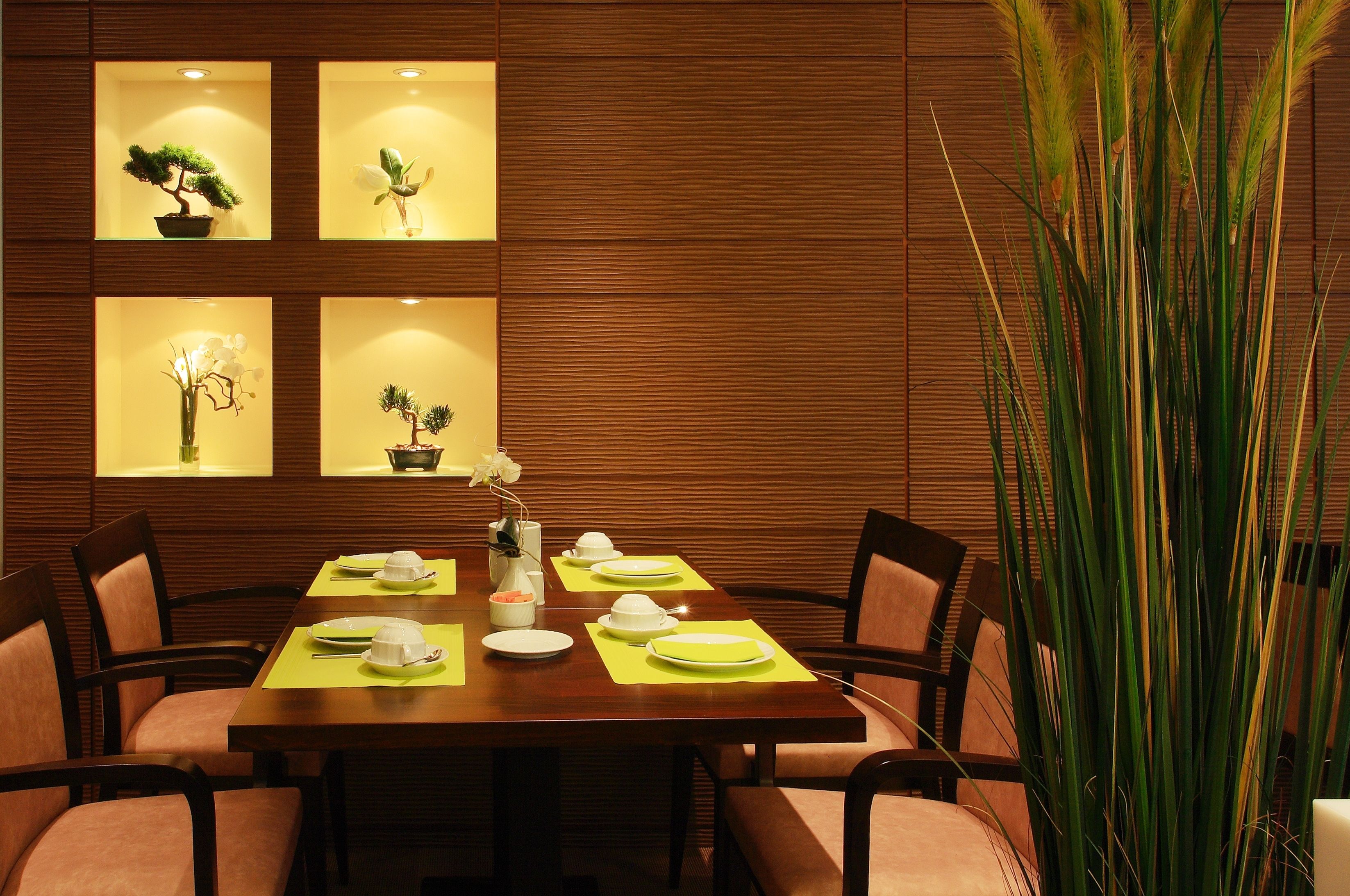 A dining area with a wooden table set for four, surrounded by chairs. There are four illuminated wall panels displaying potted plants.