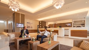 A modern hotel lobby with a reception desk, seating area, and a kitchen in the background. - Apartment-Hotel Hamburg Mitte (Hamburg)