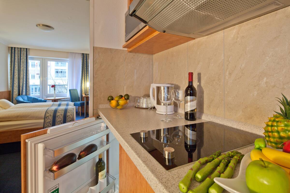 Hotelkamer met een bed, kitchenette, eethoek en uitzicht op de stad.