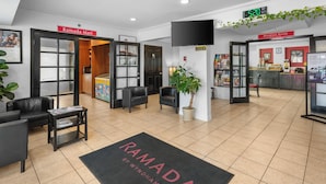 A hotel lobby with a 'Ramada by Wyndham' carpet, a 'Ramada Mart' sign, a 'Breakfast Room' sign, and a 'Caution' sign.