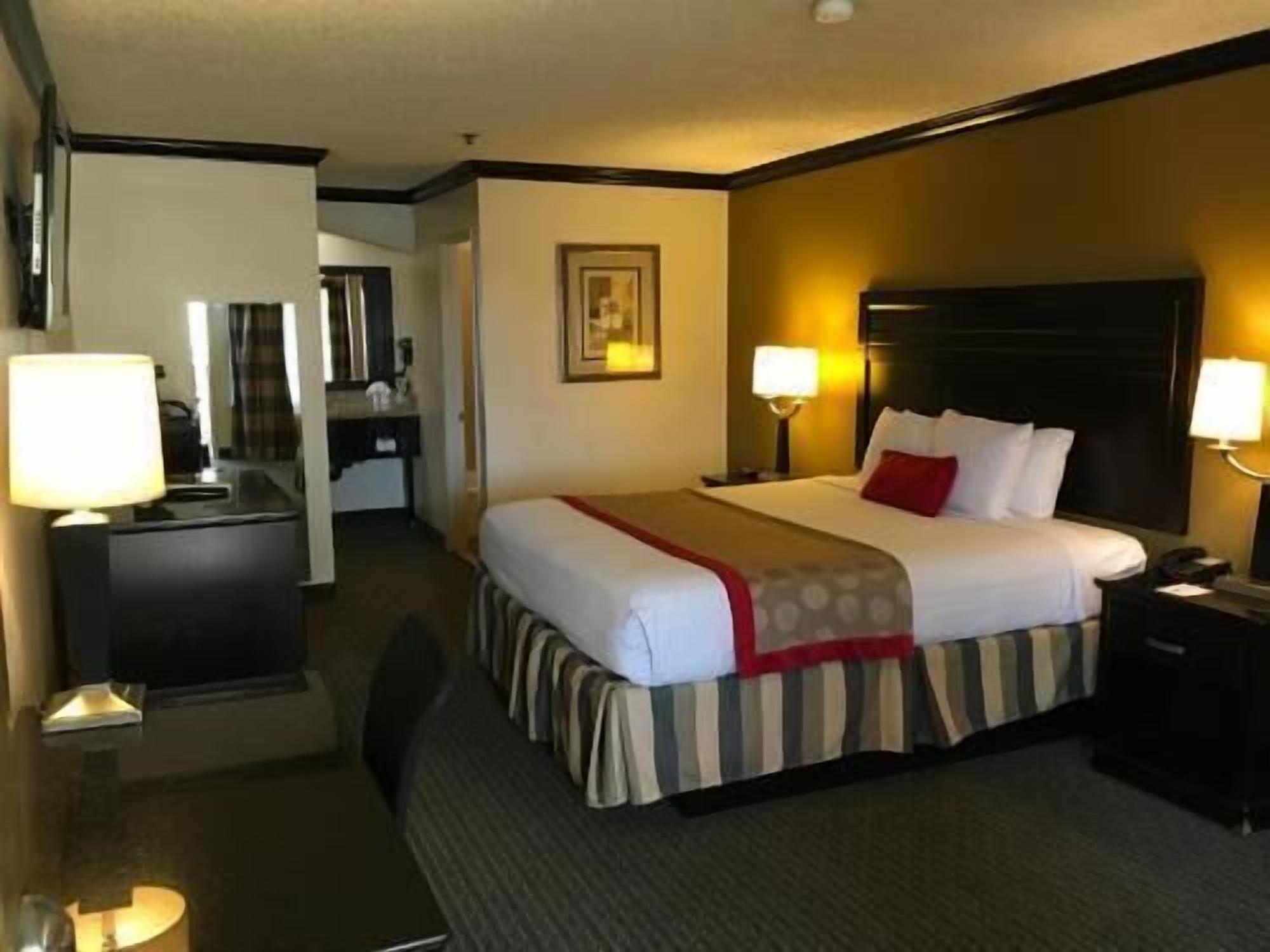 A hotel room with a bed, bedside tables, a desk, and a mirror.