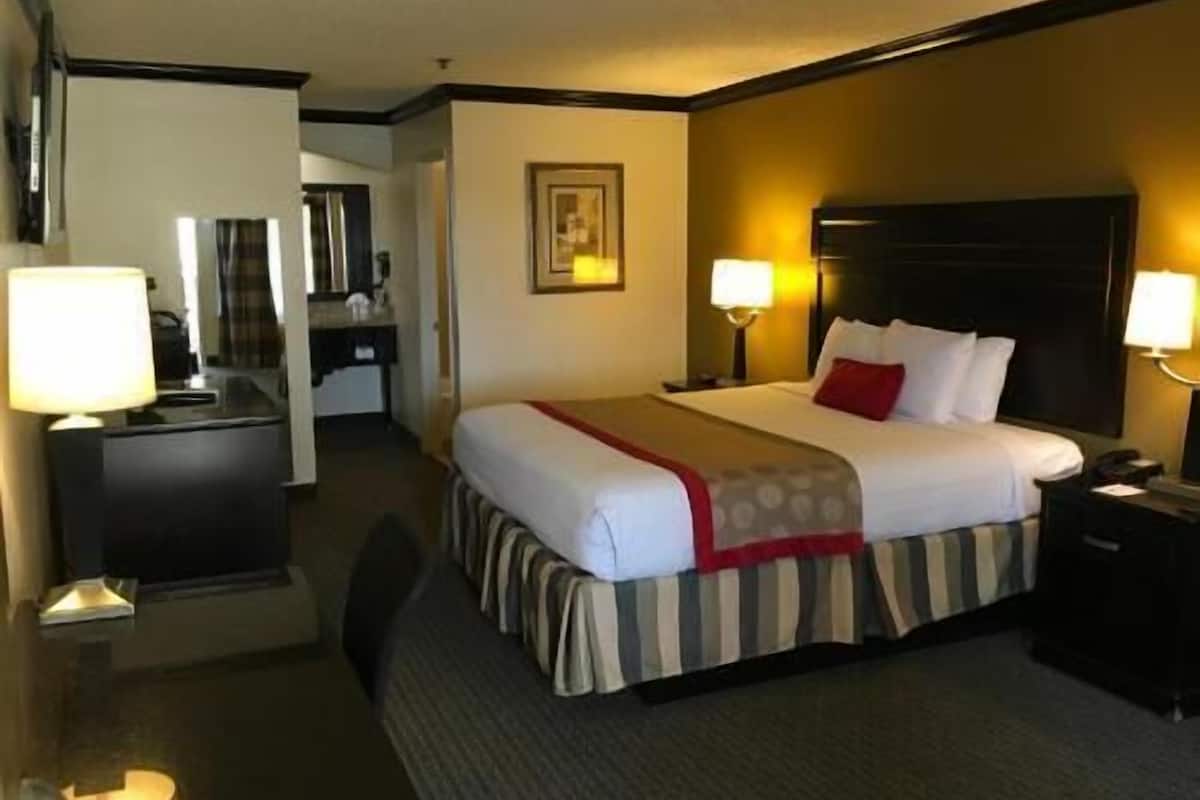 A hotel room with a bed, bedside tables, a desk, and a mirror.