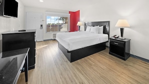 A hotel room with a bed, bedside tables, a desk, and a television.