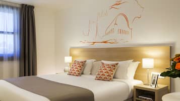 A hotel room with a large bed, two bedside tables with lamps, a wall art piece, and a window with curtains.