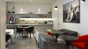A modern kitchen with marble countertops, a coffee machine, and a dining area with chairs and tables. - Citadines Presqu'île Lyon (Lyon)
