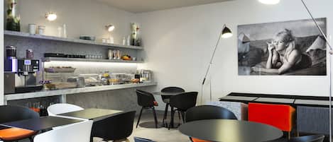A modern cafe with a bar area, seating arrangements, and a large wall-mounted artwork.