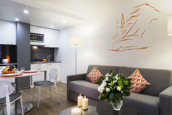 Relax in this stylish living area with a sofa, dining table, and kitchen, perfect for unwinding.