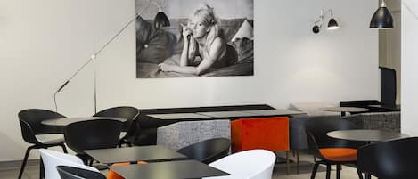 A modern cafe with black and white chairs, tables, and a large black and white photograph on the wall.