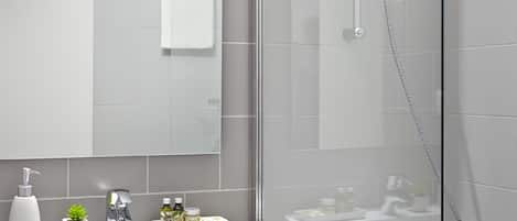 A modern bathroom with a glass-enclosed shower, a white vanity with a mirror, and a bathtub.