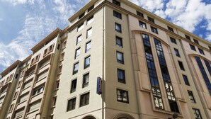 A multi-story hotel with a beige facade, large windows, and arched doorways. - Citadines Presqu'île Lyon (Lyon)